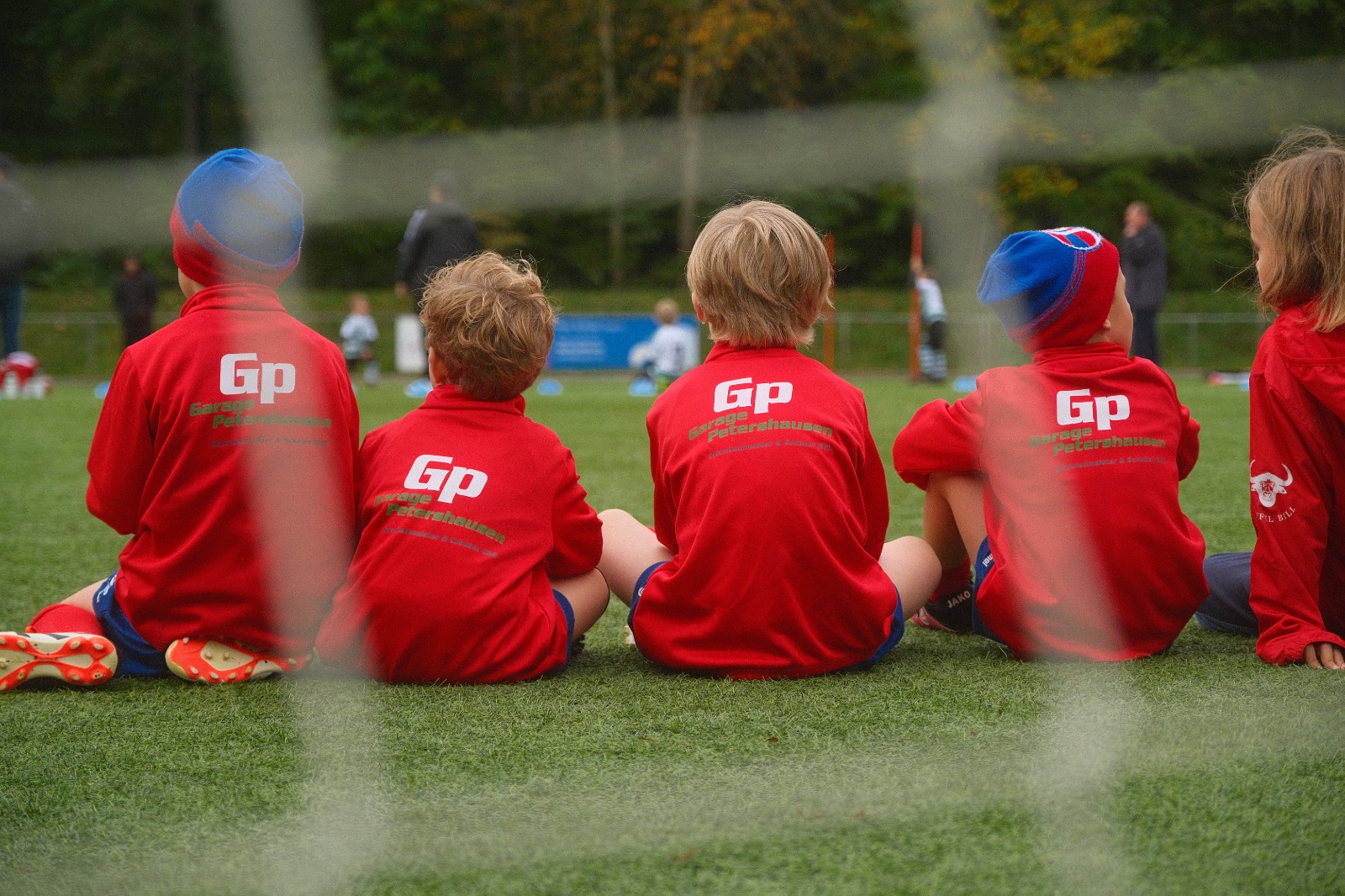 Unsere Bambini am Spielfeldrand in ihren roten Trainingsjacken
